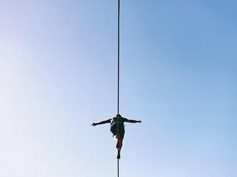 person walking on tightrope against blue sky